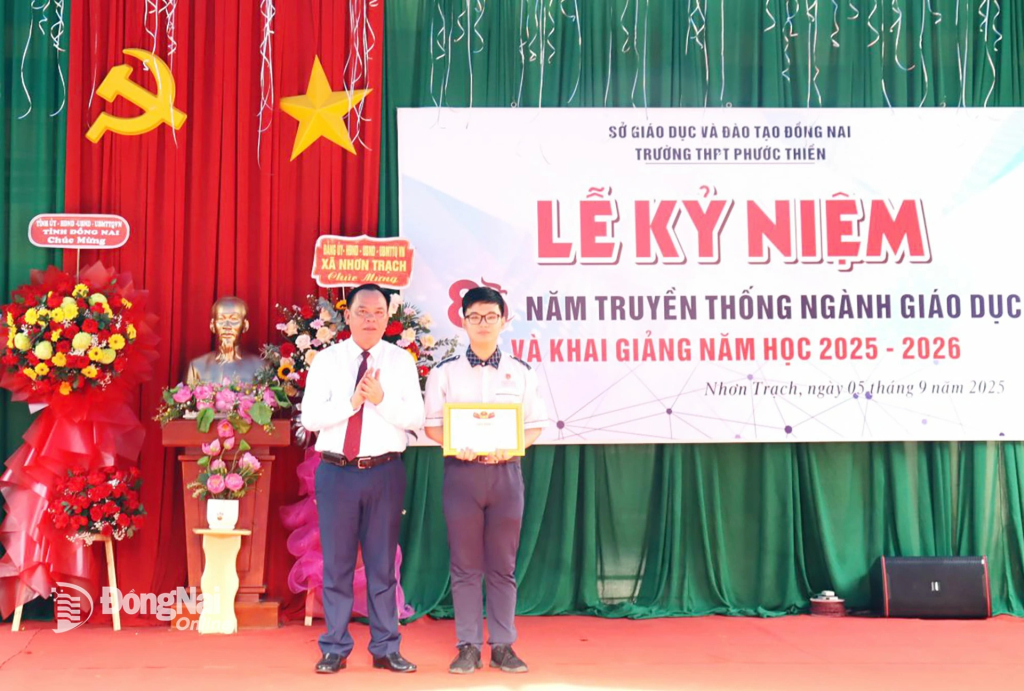Phó Bí thư Tỉnh ủy, Chủ tịch UBND tỉnh Đồng Nai Võ Tấn Đức khen thưởng học sinh Phan Ngọc Thành Minh, thủ khoa xuất sắc của trường. Ảnh: Nguyệt Hà